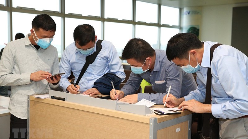 Nhân viên y tế kiểm tra phiếu khai báo y tế của hành khách trước khi làm thủ tục nhập cảnh tại cửa khẩu Nội Bài chiều 7/3. (Hình: Dương Giang/TTXVN)