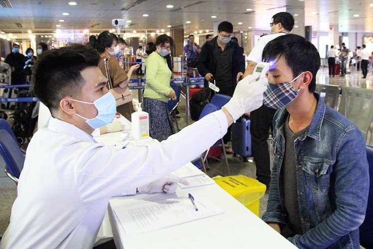 Nhân viên Trung tâm Kiểm dịch quốc tế đo thân nhiệt hành khách tại sân bay Tân Sơn Nhất. Ảnh: Hữu Nguyên.