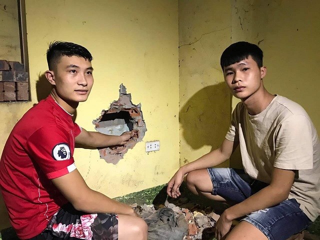 Anh Nguyễn Lương Bằng (phải) cùng một số người dân khác khoan tường cứu cháu bé bị bỏ giữa khe tường nhà trọ ở thị trấn Châu Quỳ chiều 18/8.