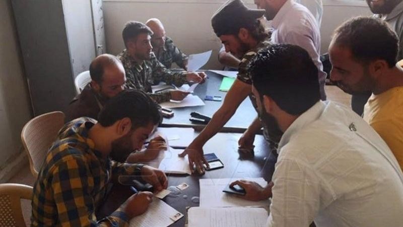 Các chiến binh làm thủ tục giao nộp vũ khí cho quân đội Syria.