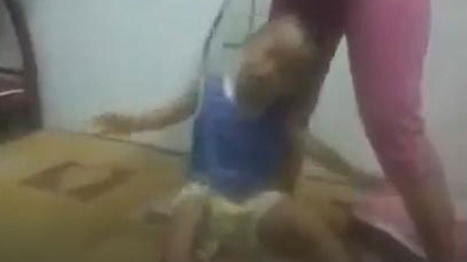 Video ghi lại cảnh một người phụ nữ khoảng 30 tuổi dùng dây thừng buộc vào cổ bé trai khoảng 3 tuổi và dùng vũ lực đánh đập