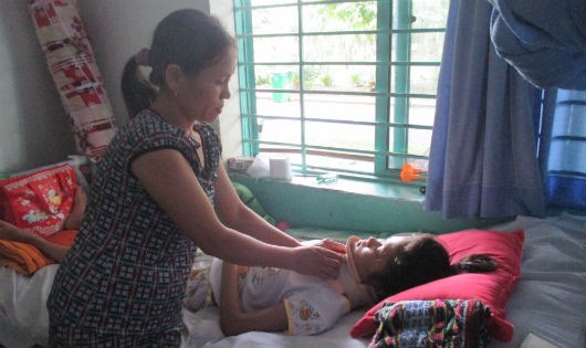 Bà Hương đang nẹp lại đốt sống cổ cho con gái. Người mẹ cho biết dù vất vả đến mấy cũng cố gắng chạy chữa cho con