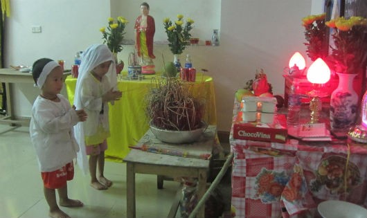 Hai đứa trẻ ngây thơ chắp tay trước di ảnh mẹ